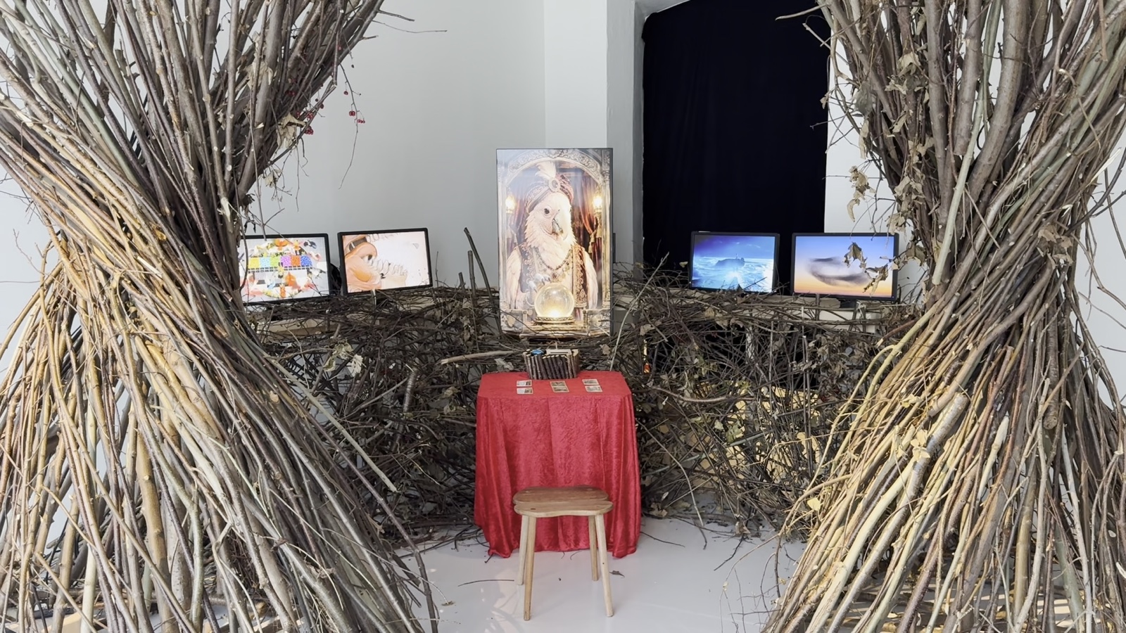 Front view of the nest installation, screens, red fortune-telling table, and stool.