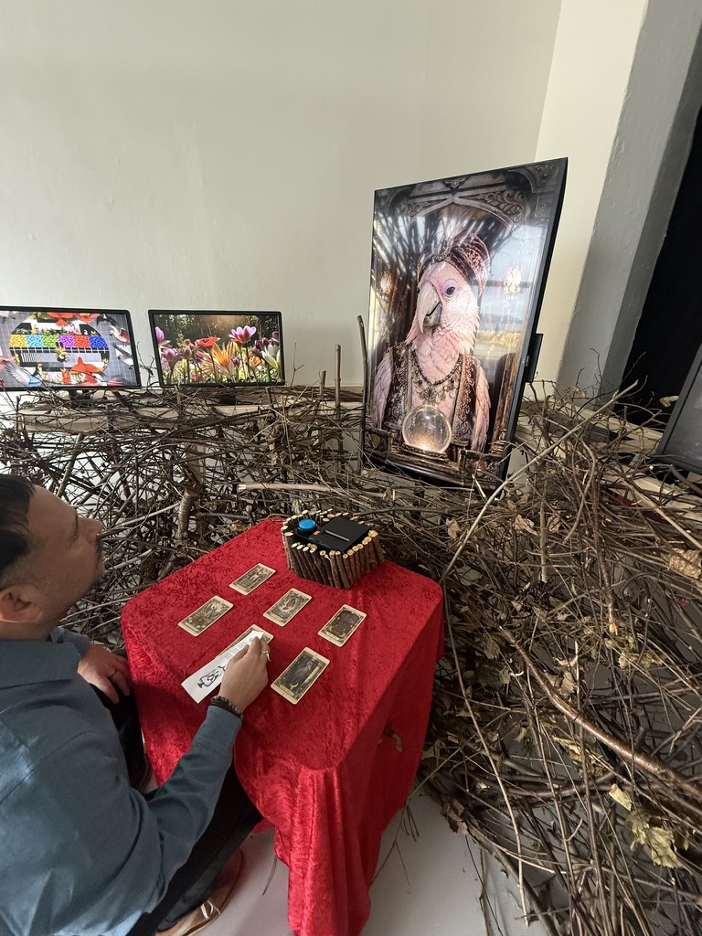 Visitor writing at the fortune-telling table beneath the cockatoo display.