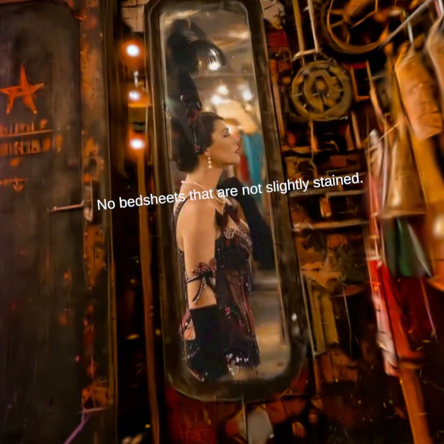 A performer in an ornate costume is reflected in a narrow mirror among gears and hanging garments.