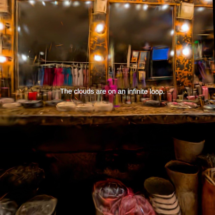 A cluttered dressing table and mirror glow in a worn theatrical backstage room.