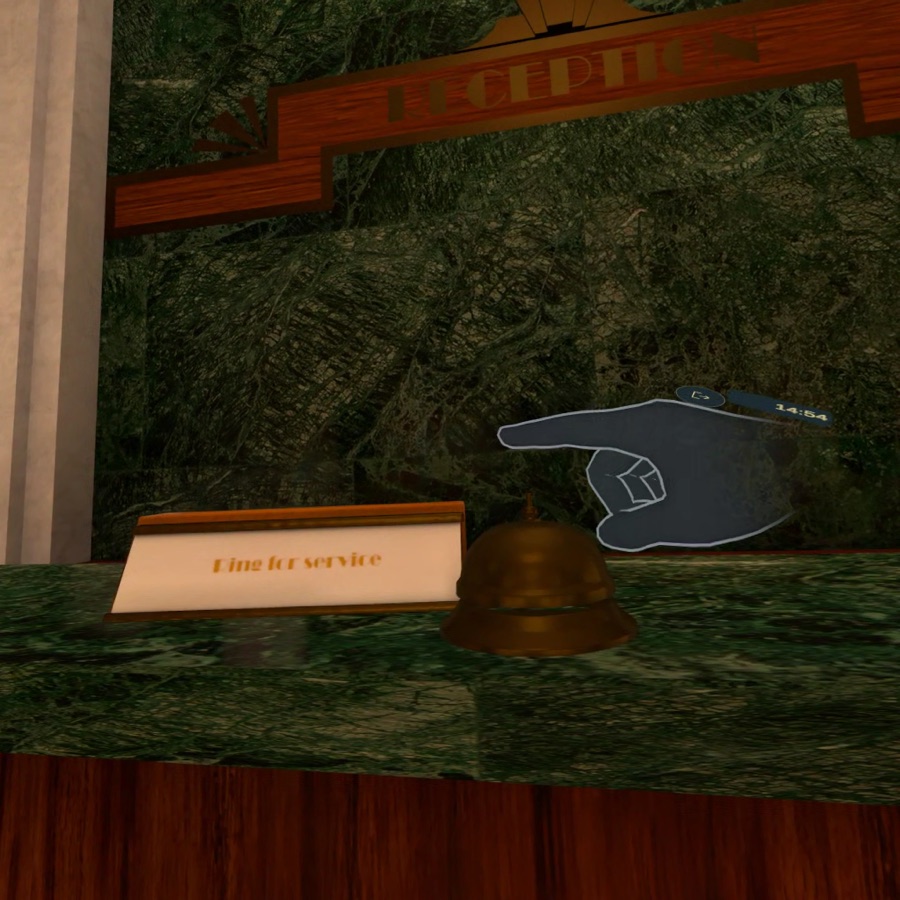 A virtual hand points toward a brass service bell on the moss-green hotel reception desk.