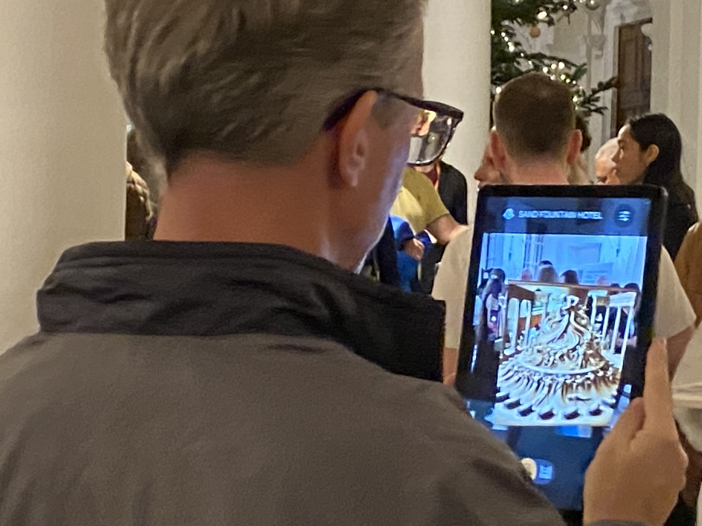 A visitor viewing the augmented-reality sand fountain scene on a tablet at ICIDS 2025.